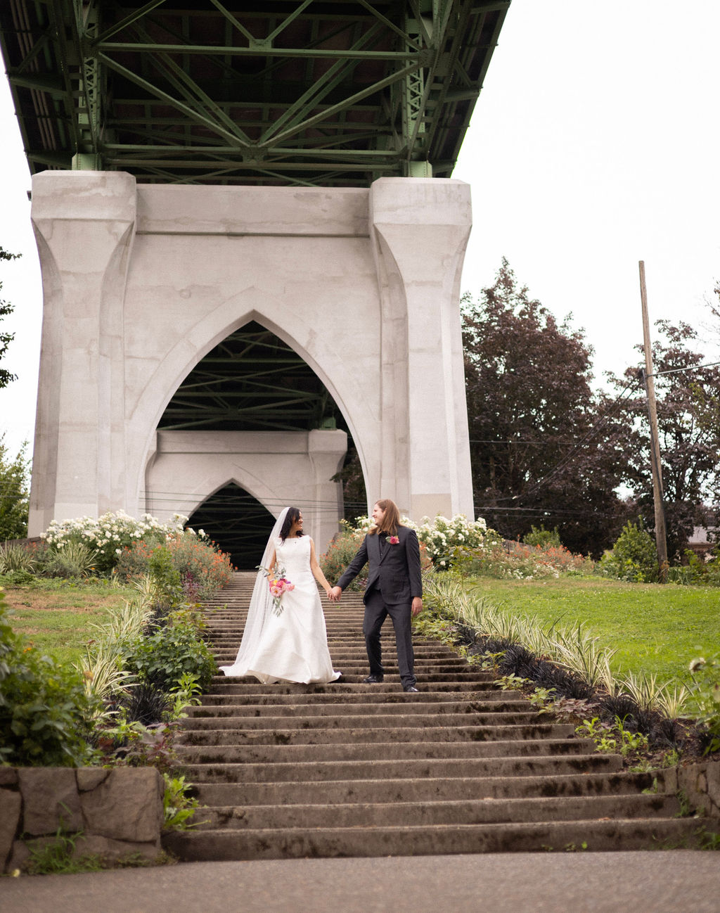 Newlyweds on the Cathedral Park staircase beneath the gothic arch of the St. Johns Bridge