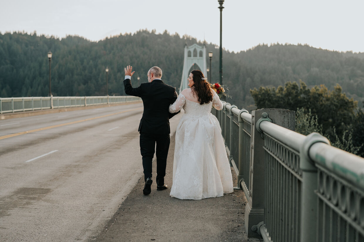 Newlyweds walking together across the St. Johns Bridge at dusk